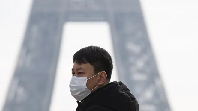 A tourist wears a face mask near the Eiffel Tower in Paris, France, 25 January 2020