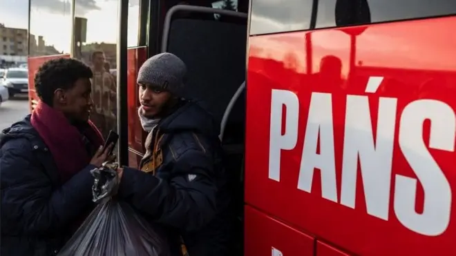 Des réfugiés montent dans un bus à la frontière polonaise