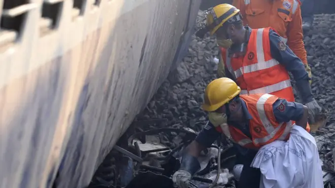 Anggota regu penyelamat India berupaya mencari korban di antara puing kereta.