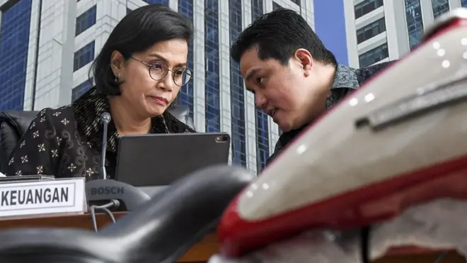 Menteri Keuangan Sri Mulyani (kiri) berbincang dengan Menteri BUMN Erick Thohir saat konferensi pers terkait penyelundupan motor Harlery Davidson dan sepeda Brompton menggunakan pesawat baru milik Garuda Indonesia di Kementerian Keuangan, Jakarta, Kamis (05/12).