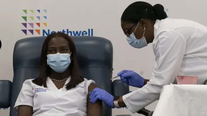 Sandra Lindsay (L) a nurse at Long Island Jewish Medical Center, is inoculated with the COVID-19 vaccine by Dr. Michelle Chester (R) in the Queens borough of New York