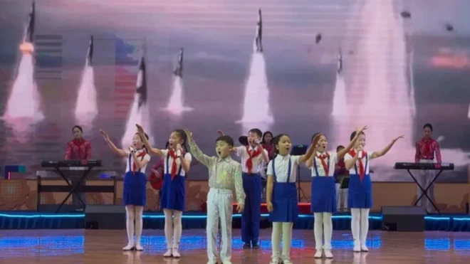 Корейские дети на сцене на фоне взлетающих баллистических ракет