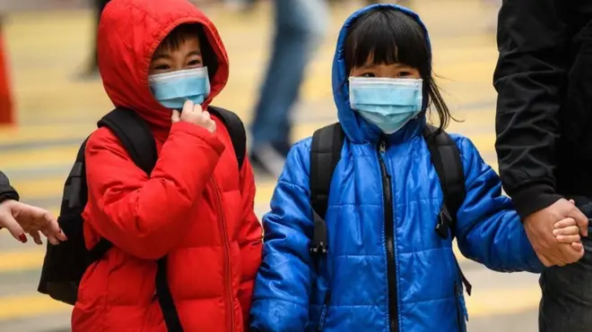 Two children wearing face masks and holding hands