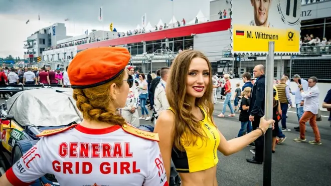 Грид-герлз выходят на трек перед началом гонки с номерами участников