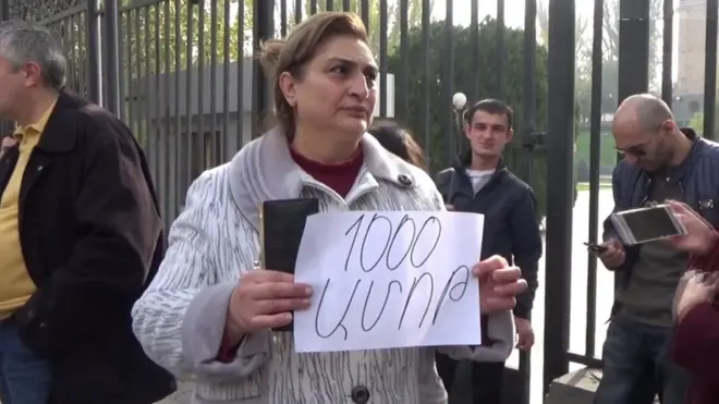 Qadının əlində "1000 dram (vermək) ayıbdır" şüarını tutur.