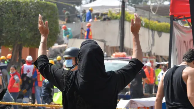 Seorang ibu menunggu kabar tentang anggota keluarganya yang berada di sekolah yang ambruk.