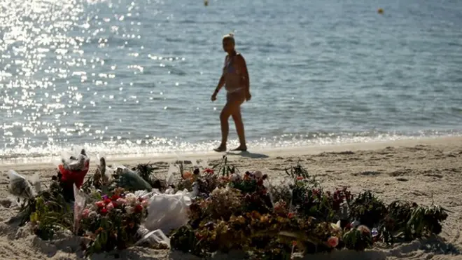 Woman walks on the beach in Sousse near flowers