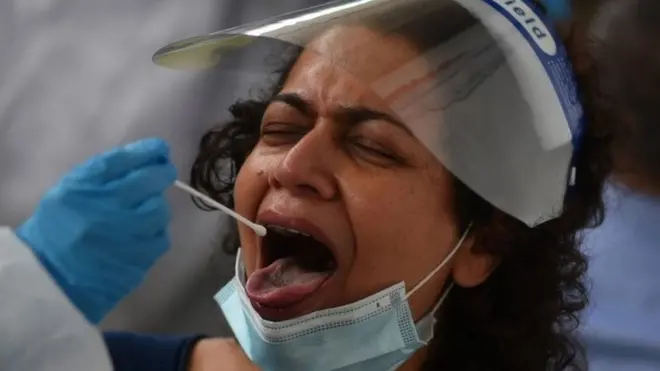 A healthcare worker collects a swab sample for the Covid-19 test, from a passenger arriving on an international flight at a facility inside the Chennai International Airport in Chennai, India, 01 August 2021.