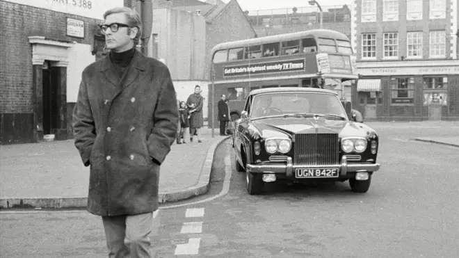 Sir Michael pictured with his first car, which he hired a chauffeur to drive for him