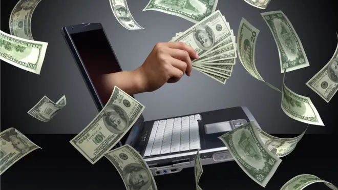 computadora y billetes de dólar