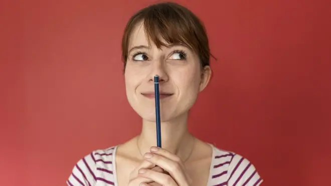 Una mujer con un lápiz pensando.