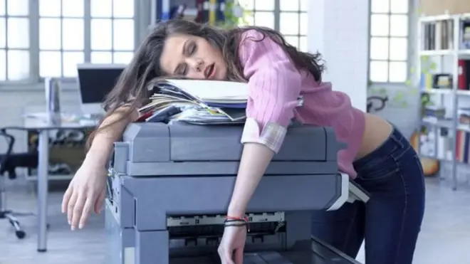 Una muchacha sobre una fotocopiadora