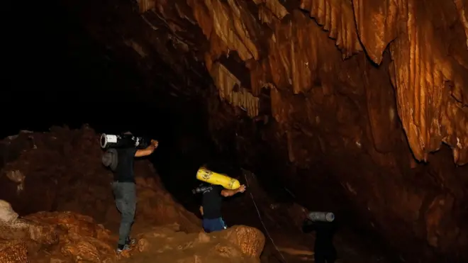 Thai rescue personnel carry oxygen tanks inside Tham Luang cave to conduct operations to find the missing members of the children"s football team along with their coach at the cave in Khun Nam Nang Non Forest Park in Chiang Rai province on June 26, 2018