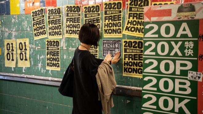 JANUARY 11: A woman pastes an anti-government poster onto a Lennon Wall in Tai Po