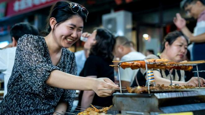 一名妇女在中国的户外烧烤摊上烧烤食物