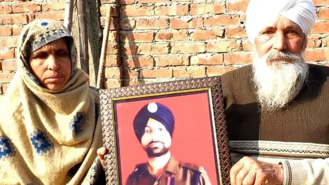 सुखजिंदर सिंह की तस्वीर लिए उनके माता-पिता