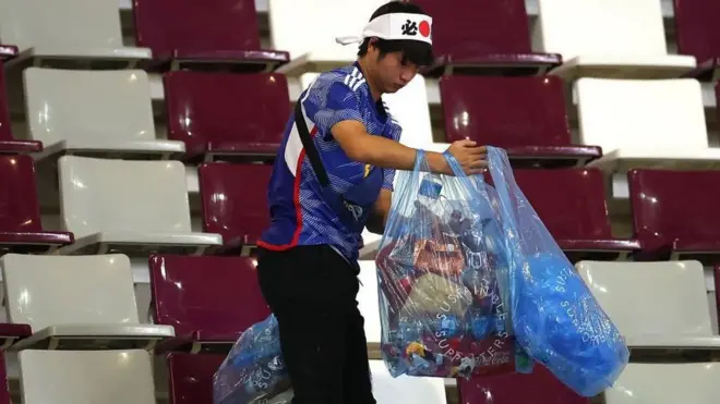 A Japan fan holding bags full of rubbish