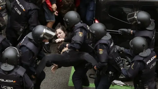 National riot police carried this woman away from a gathering outside a school in Barcelona