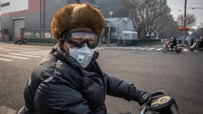 በቤይጂንግ ፊቱን በመተንፈሻ አካላት መከላከያ የሸፈነ ግለሰብ