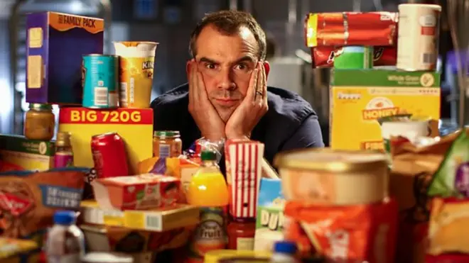 Dr Chris Van Tulleken sitting amongst a mountain of highly processed foods
