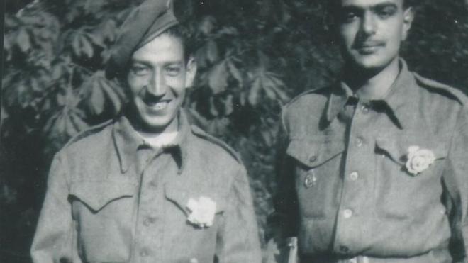 Jorge Sanjinez sosteniendo un fusil y sonriendo, junto a otro soldado.