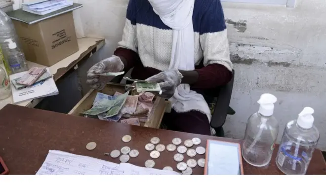 Un homme portant un masque en train de compter l'argent.