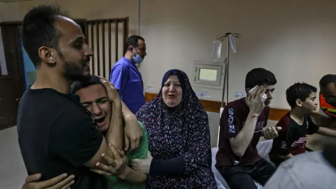 أحد أفراد عائلة أبو داير، محاطا بأقارب له، يبكي في مستشفى الشفاء بعد وفاة والده وابن عمه في غارة جوية إسرائيلية على منزل العائلة في مدينة غزة في 17 مايو/أيار 2021