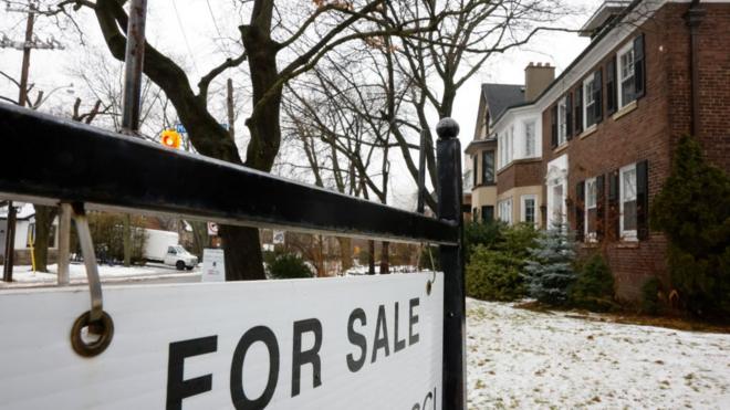 Un aviso de "Se Vende" frente a una casa en Toronto