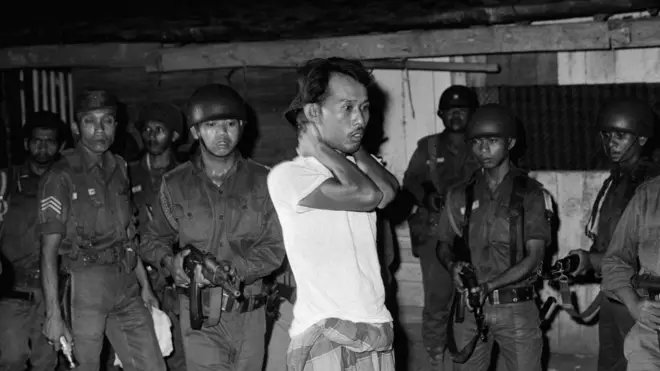 Seorang terduga simpatisan G30S dipriksa di bawah todongan senjata. Peristiwa 1965 adalah salah satu kasus pelanggaran HAM berat di masa lalu yang hingga kini penyelesaiannya masih terkatung-katung.