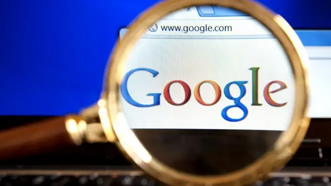 Close up to Google website through a magnifying glass on the laptop.