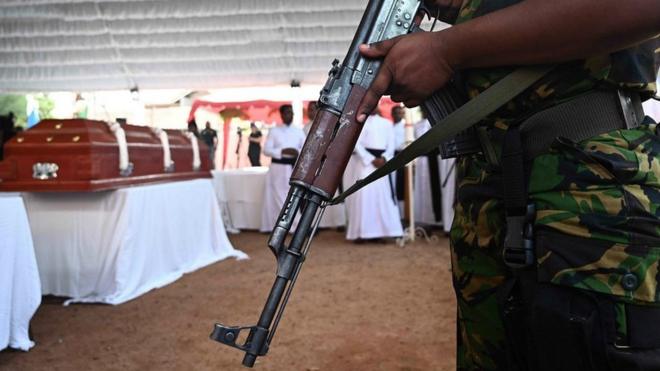 A soldier stands guard near a coffin during a funeral service at St Sebastians Church in Negombo on April 23, 2019