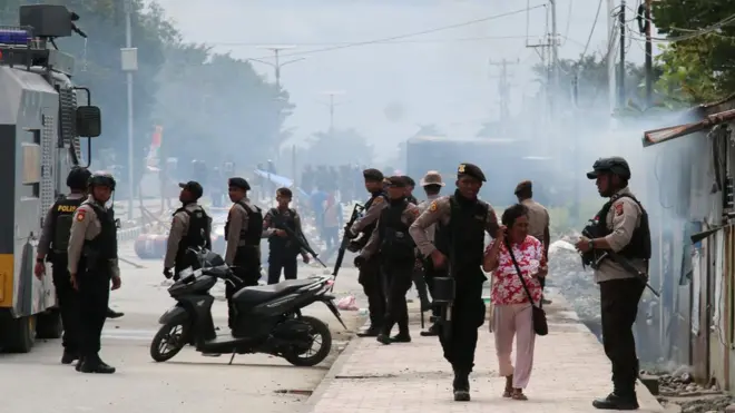 Polisi mengantar seorang ibu menjauh dari lokasi kekerasan di Mimika, Papua, 21 Agustus 2019.