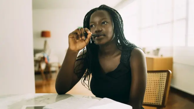 Femme africaine assise à la maison et faisant ses devoirs.
