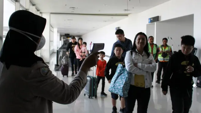 Petugas melakukan pendeteksi suhu tubuh (thermal scanner) saat penumpang pesawat tiba di terminal 2 Bandara Juanda Surabaya, yang menerima penerbangan langsung dari Wuhan, tempat asal wabah virus korona jenis baru.