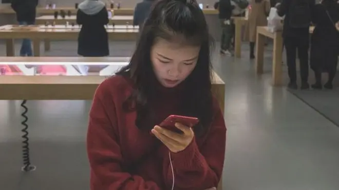 Una joven china mira un iPhone en una tienda de Apple en China.