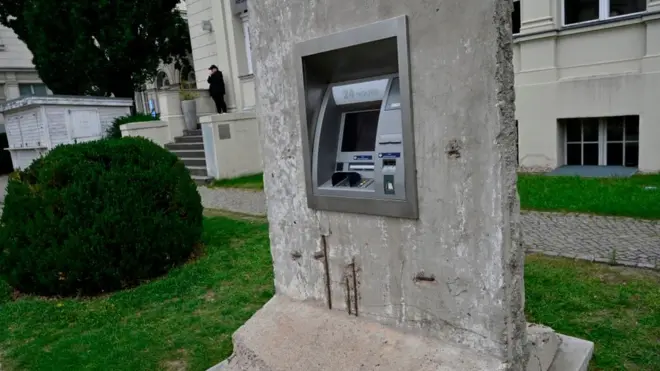 Una intervención artística en Berlín muestra un pedazo del muro que sostiene un cajero electrónico.