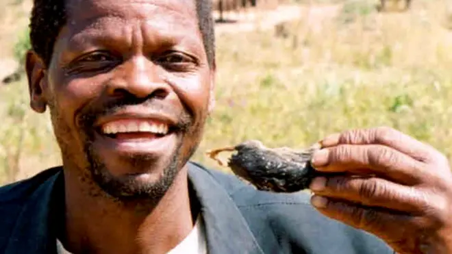 Мужчина с жареной крысой в руке