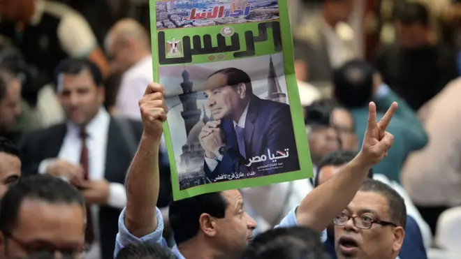 رجل يحمل صحيفة تعلن فوز عبدالفتاح السيسي بالانتخابات، في الثاني من أبريل/نيسان 2018