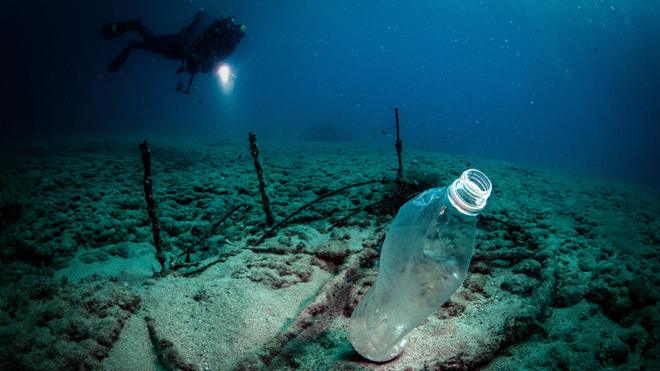 A diver with a flashlight sees a plastic bottle off the coasts of Samandag, near the Turkey - Syria border