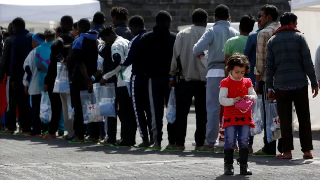 göçmenler italyada sıraya girmiş