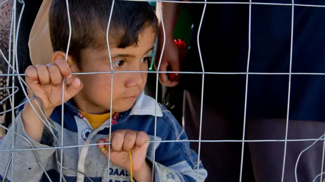 A boy waits for distribution of aid at the migrant camp in Idomeni, Greece on 23 May