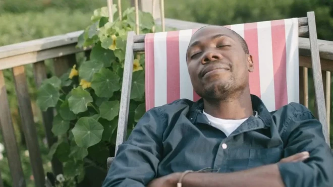 Un homme fait la sieste sur une chaise pliante