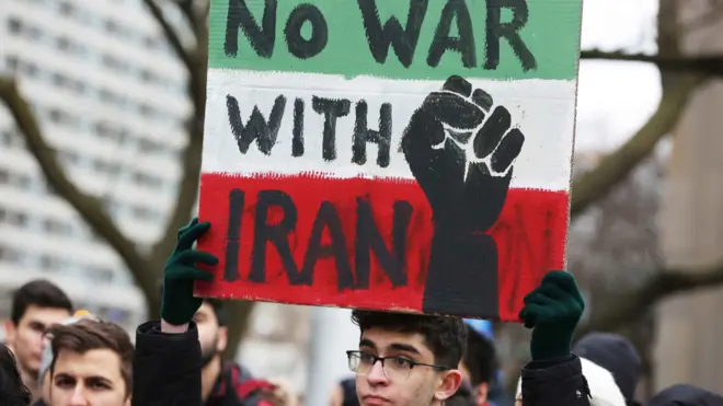 شاب يحمل لافتة تقول "لا حرب مع إيران" في مظاهرة أمام السفارة الأمريكية في تورونتو في الرابع من يناير/كانون الثاني 2020