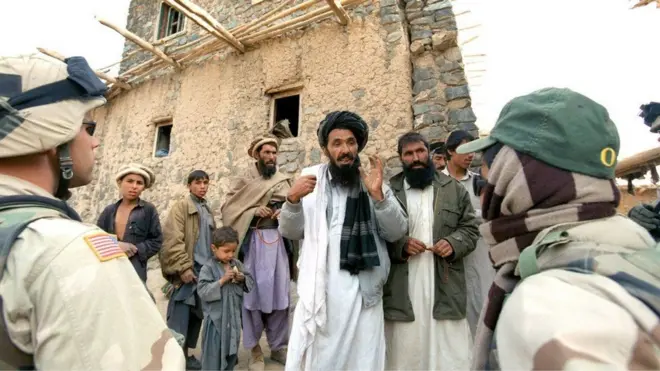 An Afghan interpreter (right) helps an American soldier to question local residents in Afghanistan. File photo