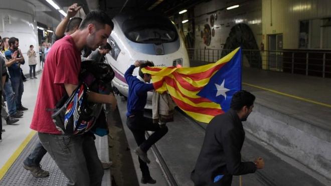 Protesters carrying a pro-independence Catalan Estelada flag jump on tracks to block trains at the Sants Station in Barcelona during a strike called by a pro-independence union in Catalonia on November 8, 2017.