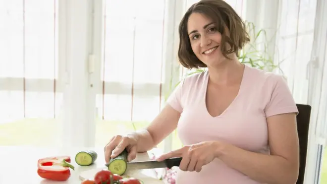 Une femme enceinte souriante prépare un déjeuner sain
