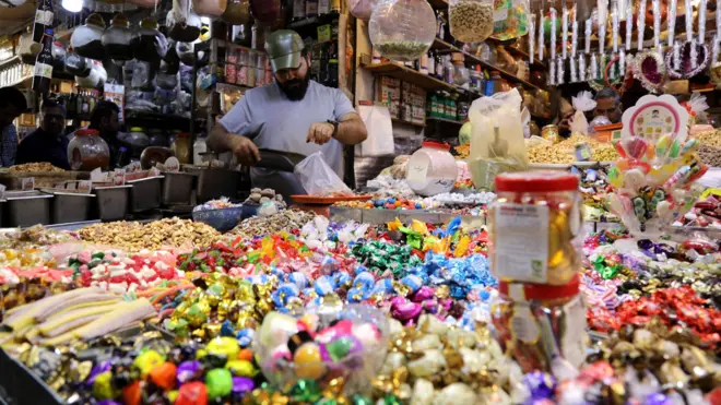 بائع يضع حلويات العيد في كيس بلاستيكي