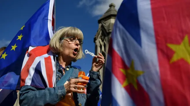 Anti-Brexit activists wave EU flags whilst draped in Union flags as they demonstrate outside the Houses of Parliament in London on September 12, 2019
