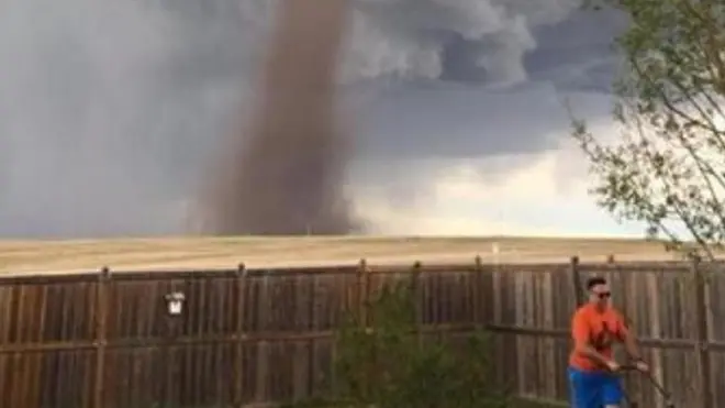 Theunis Wessels tampak tetap tenang memotong rumput sementara tornado terlihat di belakangnya.