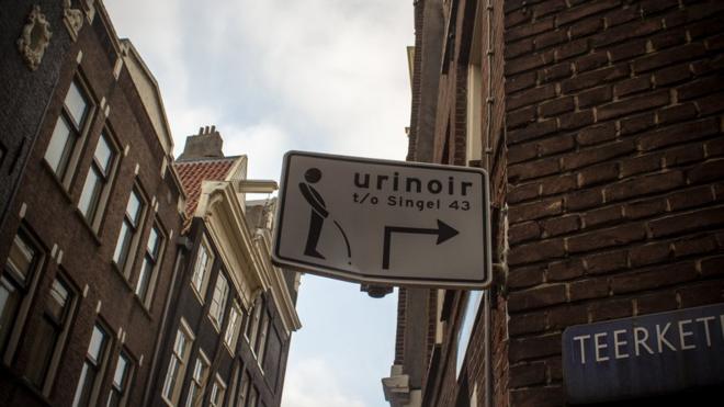 A sign pointing to a men's urinal in Amsterdam